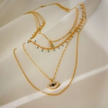 Collar multicapa dorado con ojo turco y piedras azules sobre un fondo de seda elegante - Collar de 4 capas de ojo de la suerte