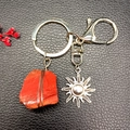 Detail of red crystal stone wrapped in wire with silver sun pendant on a keychain - Red Jasper (Sun)