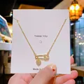 Collier trombone doré avec pendentif cœur et zircons sur carte de remerciement - Cœur Trombone