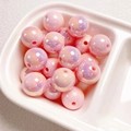 Macro shot of 14mm pink iridescent acrylic beads with center holes in a white tray - Pink
