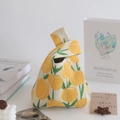 Detail of knitted tote bag featuring yellow tulip patterns and knotted handle design - Tulip Yellow