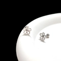 Macro shot of silver hollow flower stud earrings with screw backs on white ceramic - Steel Hollow Flower Cartilage Stud (Single)