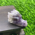 Macro detail of hand-carved purple amethyst dragon head statue on a wooden base - Purple Crystal