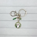 Cute cartoon panda keychain with green bamboo charm and golden ring on grey velvet background - Panda with Mask