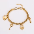 Vista dettagliata di un bracciale in acciaio inox dorato con ciondoli a cuore e chiave - Oro