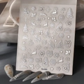 Detalle de pegatinas navideñas 3D con copos de nieve y renos sobre uñas grisáceas - CO-323 Estampado en plata