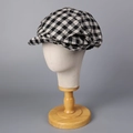 Dettaglio di un berretto newsboy retrò a quadri bianchi e neri su supporto di legno - M (56-58cm) / Nero