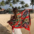 Ethnic red beach shawl with floral patterns and tassels shown in a sunny beach setting - Emerald-Multicolor Geometric Floral Red Tassel / 180cm