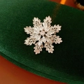 Dettaglio macro della spilla a fiocco di neve con zirconi su velluto verde scuro - Argento