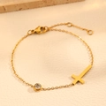 Detailopname van gouden kruisarmband met sprankelende zirkoon en karabijnsluiting - Gouden Kruis Armband