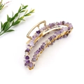 Detailed close-up of handmade banana hair claw with purple crystal stones and gold wire - Gold + Amethyst