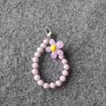 Close-up of purple beaded flower charm with yellow center and silver metal clasp - Purple Beads Purple Flower