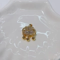Detailed view of a gold lock pendant with clear gemstones on a white ceramic tray - Longevity Lock