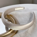 Detail of elegant champagne satin sponge headband on a minimalist white background - Beige