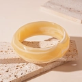 Macro detail of amber resin bangle with white marble texture on travertine stone blocks - Beige