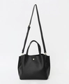 Detail of black PU leather handbag showing golden circular buckle and fine texture - Black