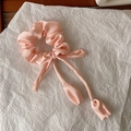 Detailed view of a pink satin scrunchie with long ribbons and petal-shaped ends - Pink