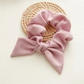 Vista detallada de un coletero rosa con lazo sobre un posavasos de tela con textura - Rosa Pasta de Frijol