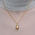 Detailaufnahme einer goldfarbenen Hand-Halskette mit einem kleinen grünen Edelstein - Goldener Mittelfinger-Anhänger