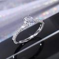 Macro shot of a four-prong round zircon ring with a sparkling pavé diamond-set band - US 5 / White Gold