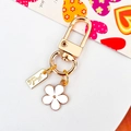 Golden keychain with white enamel flower charm and Hand Made tag on a gift card - White