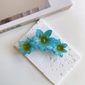 Detail of blue resin flower hair claw clip with translucent petals on a textured surface - Sky Blue