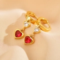 Dettaglio ravvicinato di orecchini a cuore dorati con gemme rosse e bianche su seta - Rosso (Colore Oro)