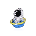 Pin's en émail astronaute assis sur une planète bleue avec un anneau doré - Style Marche sur la Planète Astronaute (CC891)