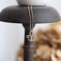 Elegant gold fleur-de-lis necklace with sparkling diamond-set pendant on wood stand - Fleur-de-lis Rose Gold