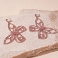 Detailed view of pink crystal butterfly earrings with sparkling stones on stone background - Pink