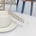 Detail of a gold headband with white pearls and rhinestones leaning on a tea cup - Pearl Style