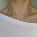 Close-up of a minimalist gold snake bone chain necklace worn by a female model - Gold Thin Snake Chain