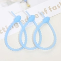 Close-up of three light blue flexible silicone cable ties with non-slip gear design - Luminous Blue