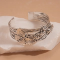 Primer plano del brazalete de plata antigua con relieves de mariposas y motivos florales - Mariposa plateada