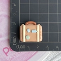Macro di mini valigia in resina rosa da 2 cm su una scala graduata di misura - Valigia Marrone