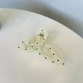 Detail shot of a cream translucent bow hair claw clip with black polka dots and metal spring - White with Bowknot
