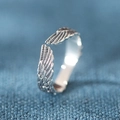 Vista dettagliata dell'anello a piuma d'argento con trama dell'ala e fascia aperta regolabile - Aperto Regolabile / Argento Tailandese