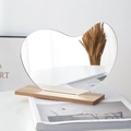 Irregular heart-shaped acrylic mirror with rectangular wooden base on a magazine - Teardrop