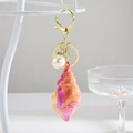 Détail du porte-clés coquillage coloré avec perle et fermoir mousqueton doré brillant - Orange