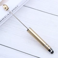 Golden metal stylus pen with black touch tip on a white wooden background - Gold
