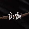 Detail shot of hollow flower-shaped stainless steel studs on a dark branch background - Steel