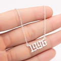 Macro shot of a 1996 silver gothic year necklace with fine link chain on hand - 1996 / Steel