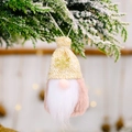 Gnome de Noël en peluche rose avec flocon doré sur branche de sapin enneigée - Style Chapeau Tricoté Jaune