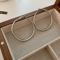 Macro shot of silver hoop earrings placed inside a textured wooden jewelry box - Silver Hoop Earrings