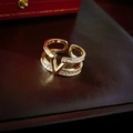 Detailaufnahme eines vergoldeten V-Rings mit Zirkonia auf dunklem Lederhintergrund - V-förmiger Buchstabe Doppelgold (63#)