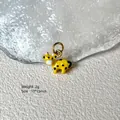 Close-up of a 10x13mm yellow cow enamel charm with black spots for jewelry making - Yellow Cow 8-43