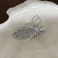 Detailed close-up of a silver bow hair clip with metal chain texture on a white shell tray - Silver Wire Wrapped