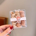 Beige and pink wavy spiral hair ties for kids in a transparent box with cartoon branding - As Shown