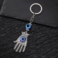 Detailaufnahme eines silbernen Hamsa-Hand-Anhängers und einer blauen Evil Eye-Perle - Kleines Auge Hamsa