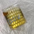 Macro view of colorful spiral hair ties in a clear plastic box on white background - Yellow
